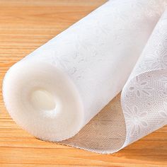 a roll of white sheer fabric sitting on top of a wooden table