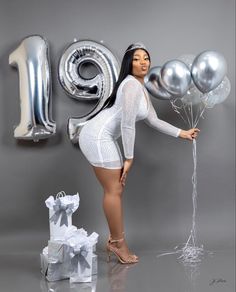 a woman is posing with balloons in front of the number one sign and present boxes