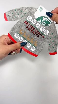 someone is holding an ornament shaped like a coffee mug cozy sweater with the starbucks logo on it