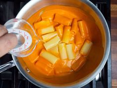 a person is stirring some food in a pot on the stove top with a measuring cup