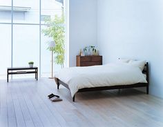 a bedroom with white walls and hardwood floors, including a bed in the foreground