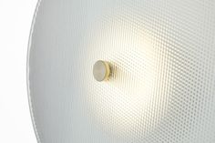 a light that is on the side of a white wall mounted speaker with a round knob