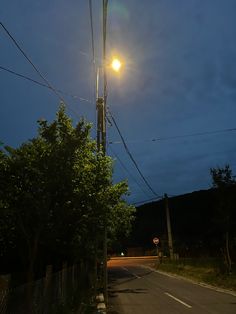 an empty street at night with the light on and power lines running across the road