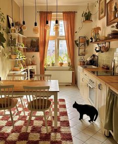 a black cat standing in the middle of a kitchen next to a table and chairs