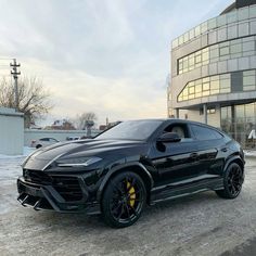 a black sports car is parked in front of a large building on a snowy day