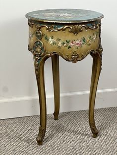 an ornately decorated side table on carpeted area with white wall and flooring