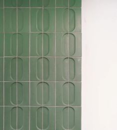 a white toilet sitting next to a green tiled wall