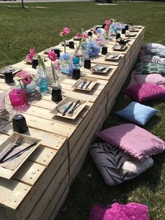 a table set up with place settings and napkins on it in the middle of a field