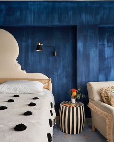 a bedroom with blue walls and black and white decor on the bed, two chairs