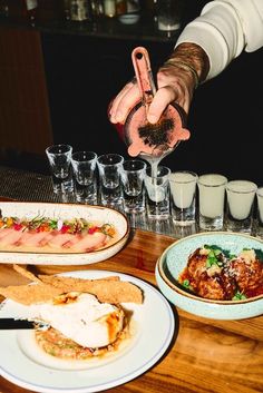 a person is reaching for some food on a table with glasses and drinks in front of them