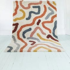 a multicolored area rug with wavy lines on the bottom, and a white wall in the background