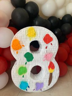 a paper plate with paintbrushes on it next to balloons in the shape of an eight