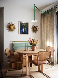 a dining room table with four chairs and a vase filled with flowers on top of it