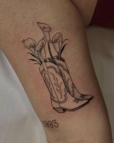 a tattoo on the leg of a woman with boots and flowers in it's boot