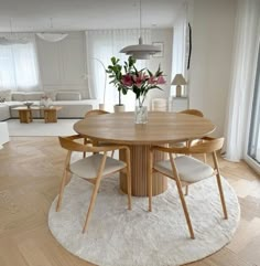 a round wooden table with four chairs around it in the middle of a living room