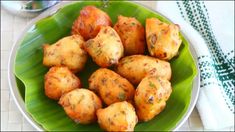 some food is sitting on a green leafy plate next to a spoon and towel