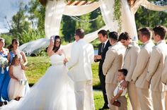 a group of people standing around each other in front of a man and woman at a wedding