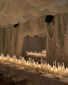 a long table covered in lots of white candles next to chairs and tables with place settings on them