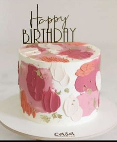 a white cake with pink and orange frosting has a happy birthday sign on top