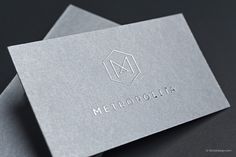 two silver business cards with the word metropolita printed on one side and the letter m on the other