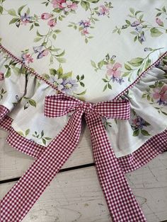 a close up of a flowered pillow on a wooden floor with ribbon tied around it