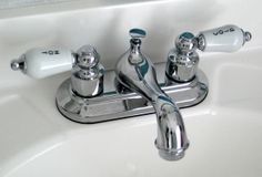 two chrome faucets sitting on top of a white sink next to each other