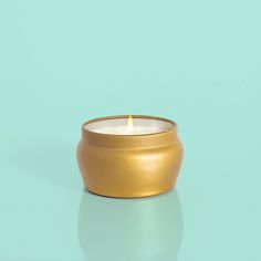 a gold candle sitting on top of a blue table next to a green wall and floor