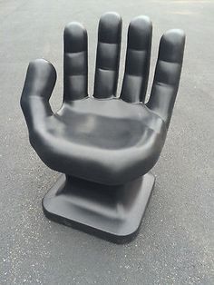 a black plastic hand that is sitting on top of a cement ground with it's fingers extended