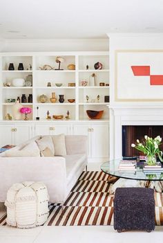 a living room filled with furniture and a fire place next to a white book shelf