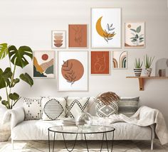 a living room filled with white furniture and lots of pictures on the wall above it