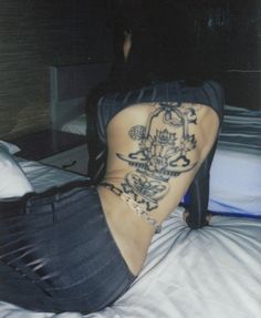 a woman sitting on top of a bed with tattoos on her lower back and legs