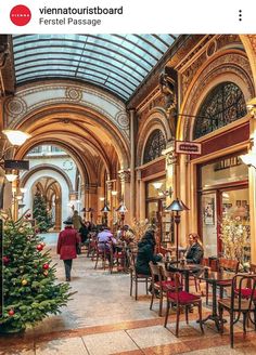 people are sitting at tables in the middle of an indoor mall with christmas decorations on display