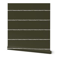 a dark green roller blind with white dots on the top and bottom, against a white background