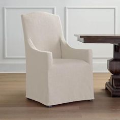 a white chair sitting next to a wooden table on top of a hard wood floor