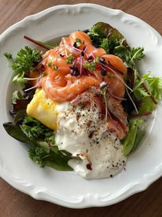 a white plate topped with lots of food on top of a wooden table