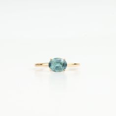 an oval cut blue topazte ring on a white background, with the center stone set in yellow gold