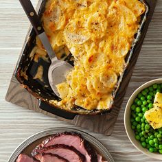 two plates with meat, potatoes and peas on them next to a casserole dish