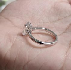 a hand holding a ring with a diamond in it's center and the middle finger