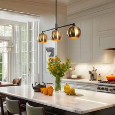 a kitchen with white counter tops and yellow flowers in a vase on the center island