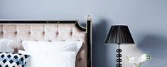 a bedroom with blue walls and two lamps on either side of the headboard,