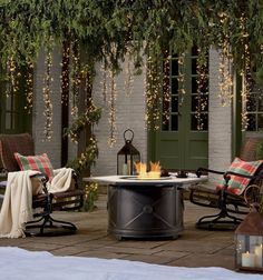 a fire pit sitting on top of a patio covered in christmas lights and greenery