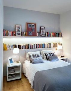 there is a bed with many books on the shelves above it and a lamp next to it