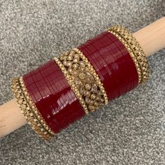 a wooden stick with some red and gold bracelets on it's end,