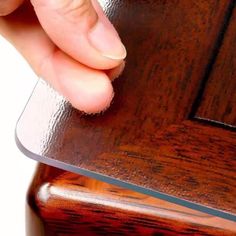 a close up of a person's hand holding a piece of glass on top of a wooden table