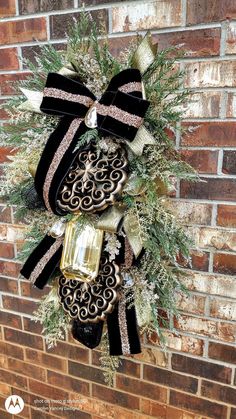 a black and gold christmas wreath hanging on the side of a brick wall with ornaments around it