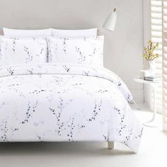 a bed with white sheets and blue flowers on it