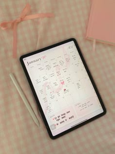 a calendar and pen sitting on top of a pink table cloth next to a notebook