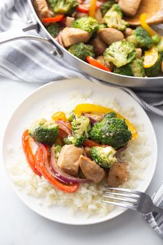 a white plate topped with chicken and veggies next to a pot of broccoli