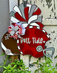 a red and white football helmet shaped door hanger with the word pou - tue on it