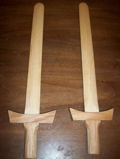 two wooden handles on top of a wood table next to each other, one with an arrow in the middle